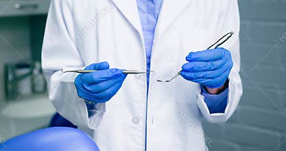 Black Dentist With Afro Holds Dental Instruments, Ready for Examination in Clinic
