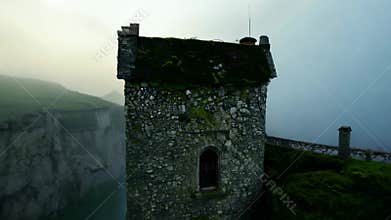 A mysterious stone tower on the foggy mossy cliff.