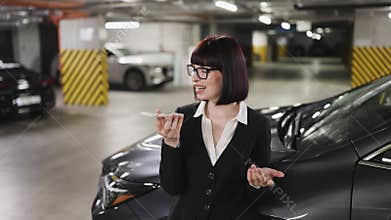 Businesswoman recording audio message in indoor parking garage