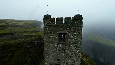 A mysterious stone tower on the foggy mossy cliff.