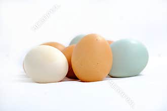 Multicolored village chicken eggs and duck eggs on white.