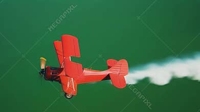 Red biplane performing aerobatics on green screen background