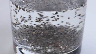 Chia seeds stirred in a glass of water, gradually forming a gel-like texture as