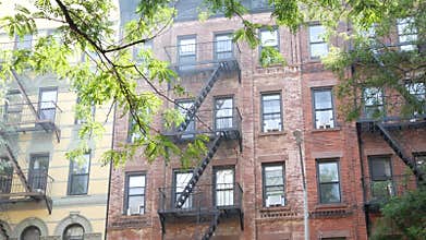 New York City building architecture, Manhattan. Residential house exterior. Red brick, fire escape.