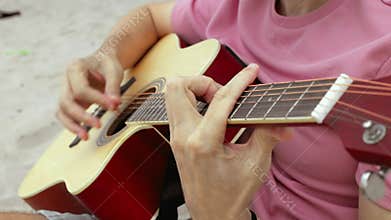 Strumming acoustic guitar on beach with closeups of chord progressions and finger movements