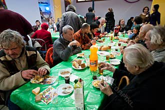 Homeless people sit around table at the Christmas charity dinner for the poor people