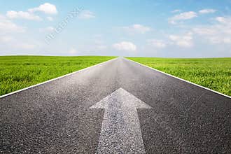 Arrow sign pointing forward on long empty straight road