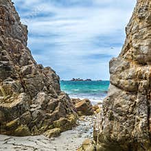 Exploring the rocky coastline of Crozon in Bretagne and admiring the distant island under a cloudy sky