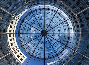 Striking Upward View of a Grand Circular Glass Dome and Its Intricate Framework, Surrounded by Modern Curved Skyscrapers
