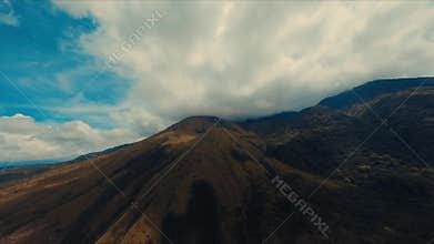 Aerial view of a majestic mountain under a dramatic sky with sweeping clouds