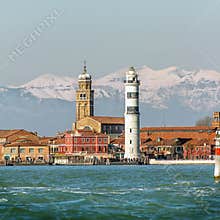 Scenic Murano Lighthouse and Historic Bell Tower Standing Against Distant Snow-Capped Alps on a Bright Day in the Venetian Lagoon