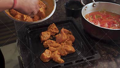 Marinated chicken cooking on griddle with curry sauce pot