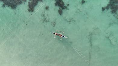 Overhead drone shot of two fishermen casting a fishing net from a smal