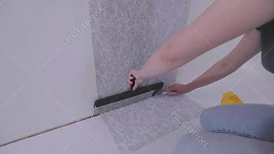 Trimming wallpaper in the corners of a room after wallpapering. Trimming excess paper.