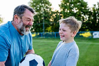 Dad and son having fun while practicing football outdoors.