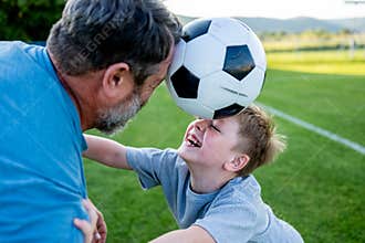 Dad and son having fun while practicing football outdoors.