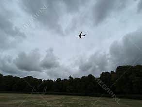 Commercial Airplane Flying Over Amsterdam Forest Under Cloudy Sky Netherlands
