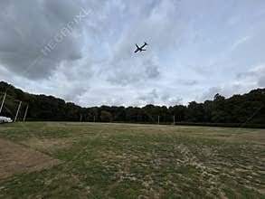 Commercial Airplane Flying Over Amsterdam Forest Under Cloudy Sky Netherlands