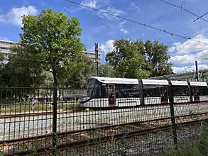 Modern tram beside trees and apartment blocks on urban rail line under