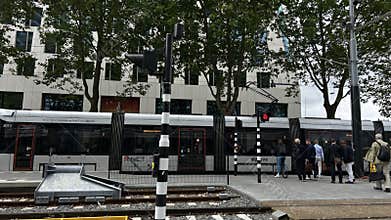 Amsterdam Zuida business district tram stop with commuters beside modern office