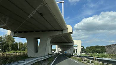 Modern highway under elevated bridge with curving road, concrete support