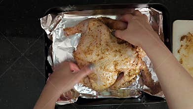 A horizontal video showing a fresh chicken being marinated for baking in the oven.