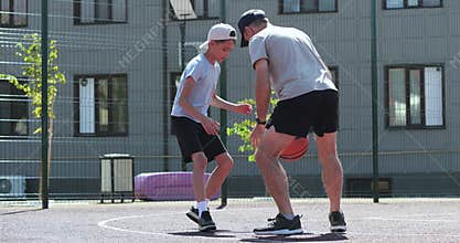 Father and son playing basketball outdoors show family fun and energy. Dad and child playing basketball builds trust and