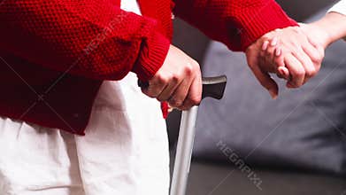 A Caregiver's Gentle Hand Supporting an Elderly Person Using a Walking Cane