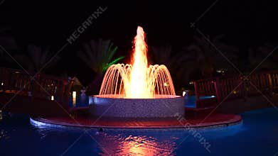 The fountain in swimming pool at luxury hotel in night illumination