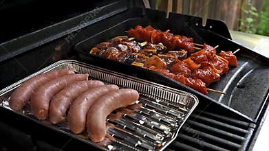 Sausages and Marinated Skewers Grilling on Outdoor Barbecue