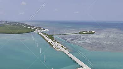 Aerial view of turquoise ocean, mangrove island and Overseas Highway in Florida Keys with boats and clear water. g