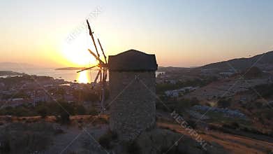 Aerial drone circles historic stone windmill above Foca at sunset on Aegean coast in Turkiye, historic mill, stone tower, izmir
