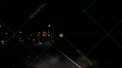 Night driving view along curving road with streetlights, traffic signals, and