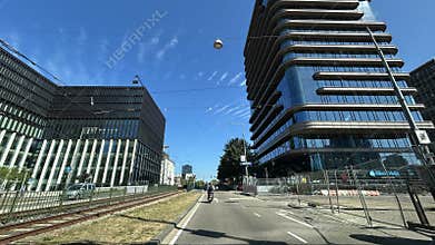 Modern office district street with glass skyscrapers, tram tracks, scooter rider