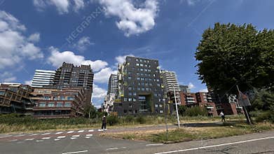 Modern residential and office towers rising beside wide city road under bright