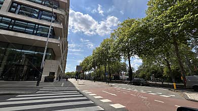 Modern office street beside glass facade, tree lined boulevard, crosswalk
