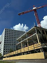 Red tower crane above modern urban building under clear blue sky with