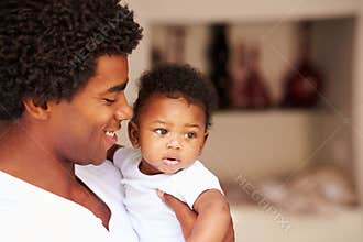 Dad Cuddling Baby Son At Home