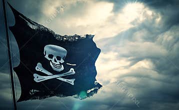 Ripped tear grunge old fabric texture of the pirate skull flag waving in wind, calico jack pirate symbol at cloudy sky with sun ra