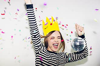 Birthday party, new year carnival. Young smiling woman on white background celebrating brightful event, wears stripped