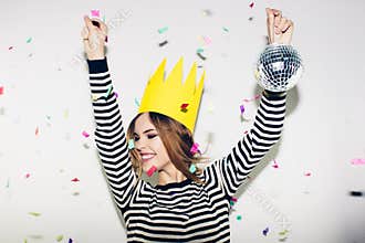 Birthday party, new year carnival. Young smiling woman on white background celebrating brightful event, wears stripped