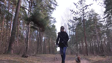 Woman playing with her dog and walking towards camera.