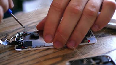The master parses the broken phone, takes out of it small details with a special screwdriver. 4K 30fps