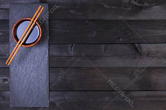 Background for sushi. Soy sauce, chopsticks on black table. Top view with copy space