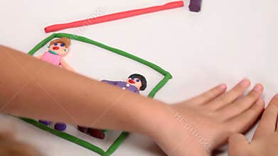 Child making a happy family house from plasticine