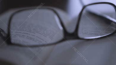 Old books on desktop with modern glasses