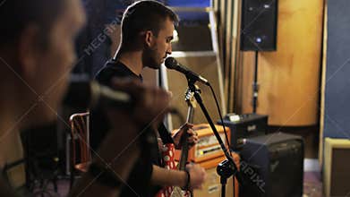 Two Young Men Singing, One of Them is Playing a Guitar