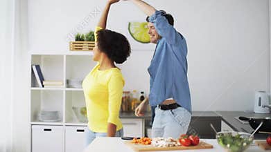 Happy couple cooking food and dancing at home