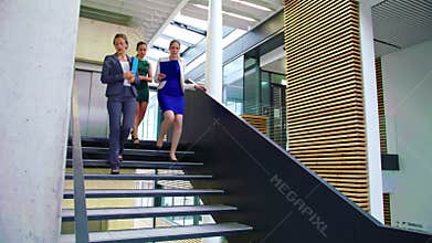 Businesswomen interacting with each other while walking on stairs