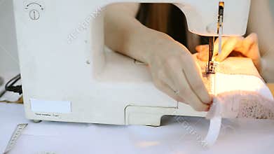 Seamstress on sewing machine scribbling piece of pink fabric.